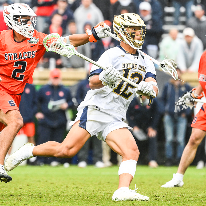 Notre Dame lacrosse player driving past Syracuse defenders